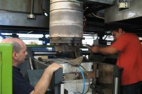 Removing the extrusion die from the blow molding machine.